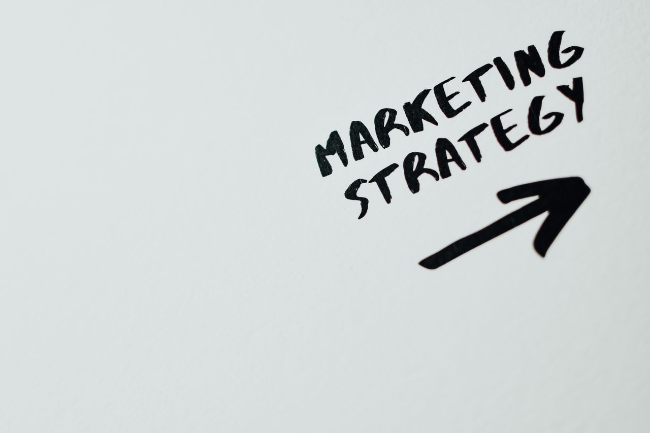 about-02 Close-up of handwritten 'Marketing Strategy' text with an arrow on white background.